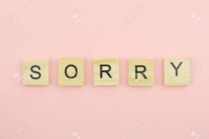 Text wooden blocks spelling the word sorry on pink background